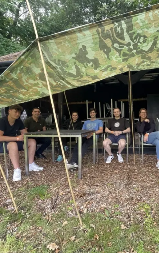 Employees sitting under a camo shelter