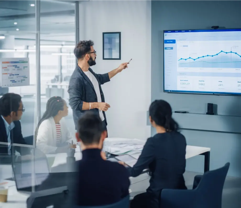 Man pointing at a presentation with colleague around table